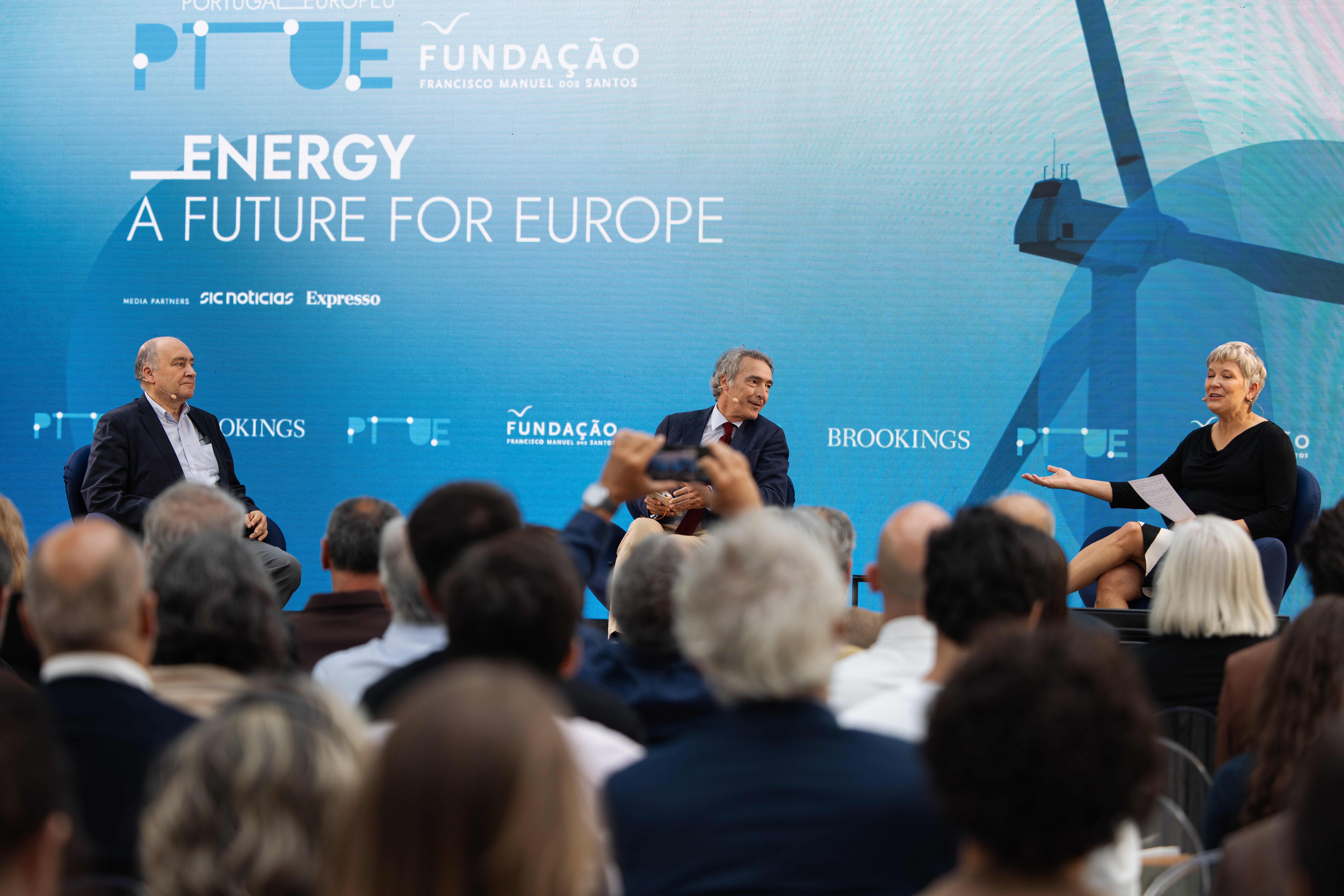 Três pessoas sentadas no palco. Uma plateia a assistir. Texto "Energy, a future for Europe".