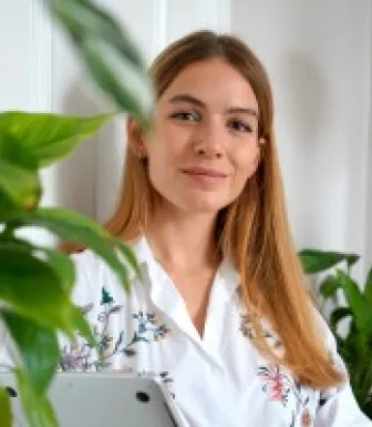 A jovem jornalista húngara, Lili Rutai, sentada tendo uma parede branca como fundo. Crédito: Lili Rutai 