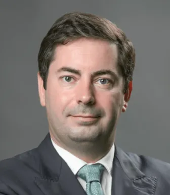 Retrato de Luís Rebelo, especialista em transição energética, num fundo cinzento escuro.
