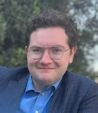 Retrato a cores do analista Decker Eveleth, num fundo com vegetação.