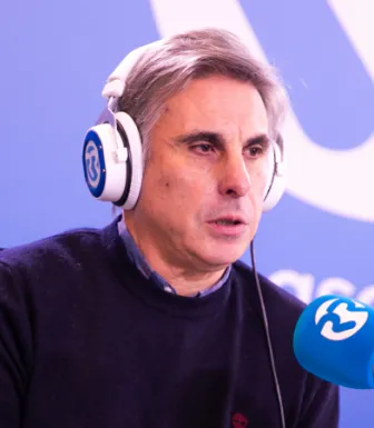 Retrato do professor João Canário, de fones na cabeça, a falar para um microfone.