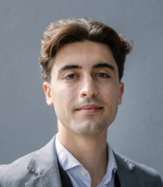 Um homem com 25 anos, de camisa de riscas sob fundo neutro. D/R.