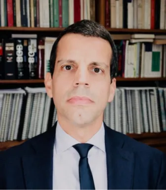 Imagem do advogado João Oliveira Geraldes, com uma estante de livros ao fundo.