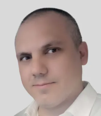 Retrato a cores de um homem, vestido com uma camisa branca. Fundo claro.