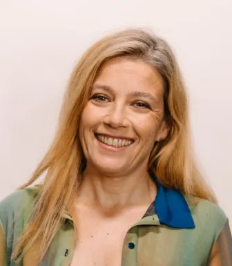 Retrato a cores da neurologista Raquel Gil-Gouveia, vestida com uma camisa às cores. Fundo claro.