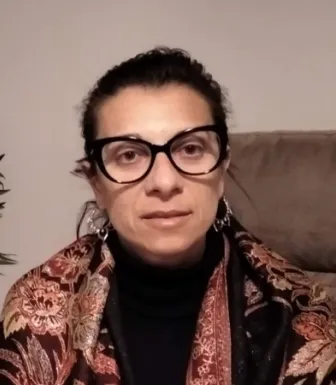 Imagem de uma mulher sentada num sofá, com uma planta ao lado.