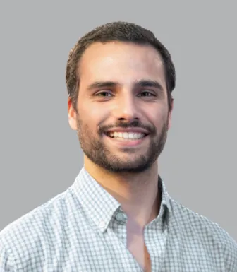 Imagem de um rapaz jovem, vestido com uma camisa aos quadrados. Fundo cinzento.
