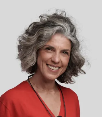 Imagem de uma mulher, a sorrir, vestida com uma camisola vermelha e um colar ao pescoço.