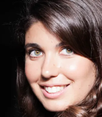 Imagem de uma mulher jovem, a jornalista Sara Capelo, sob um fundo escuro. Crédito: D/R