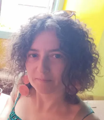 Imagem de uma mulher, com um top verde e brincos laranja.