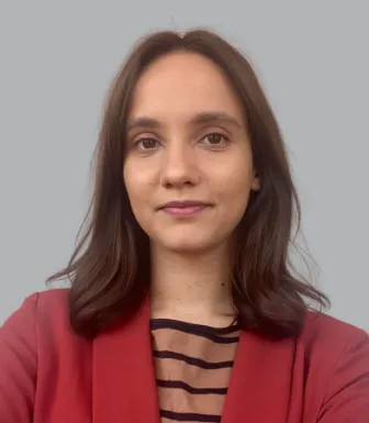 Retrato a cores de uma rapariga, de cabelo castanho e liso, vestido com um casaco vermelho e uma camisola às riscas. 