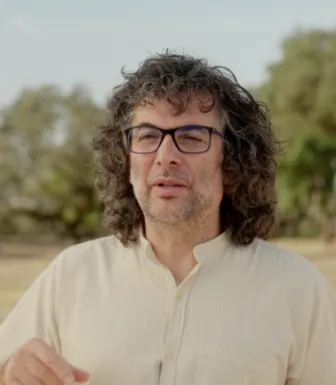 Retrato a cores de um homem, que usa óculos, e veste uma camisa clara. 
