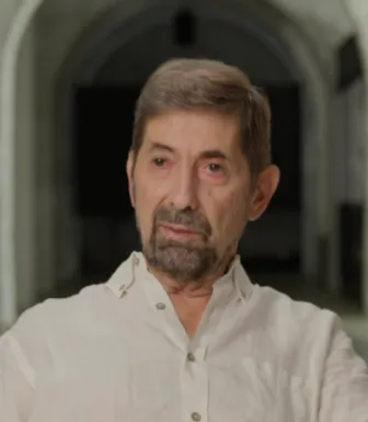 Retrato a cores de um homem, de cabelo e barba castanha, vestido com uma camisa branca.