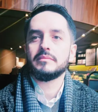 Retrato a cores de um homem com barba, a olhar para o lado, vestido com roupa de inverno.