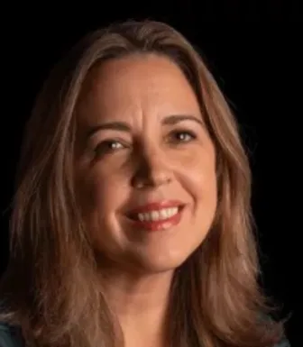 Retrato a cores de uma mulher sorridente, de cabelo castanho, sobre um fundo preto.