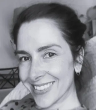 Retrato a preto e branco de uma mulher, a sorrir. Está de cabelo atado. D/R