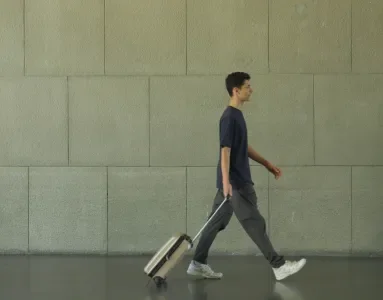 Imagem de um rapaz com uma mala de viagem, a caminhar num aeroporto.