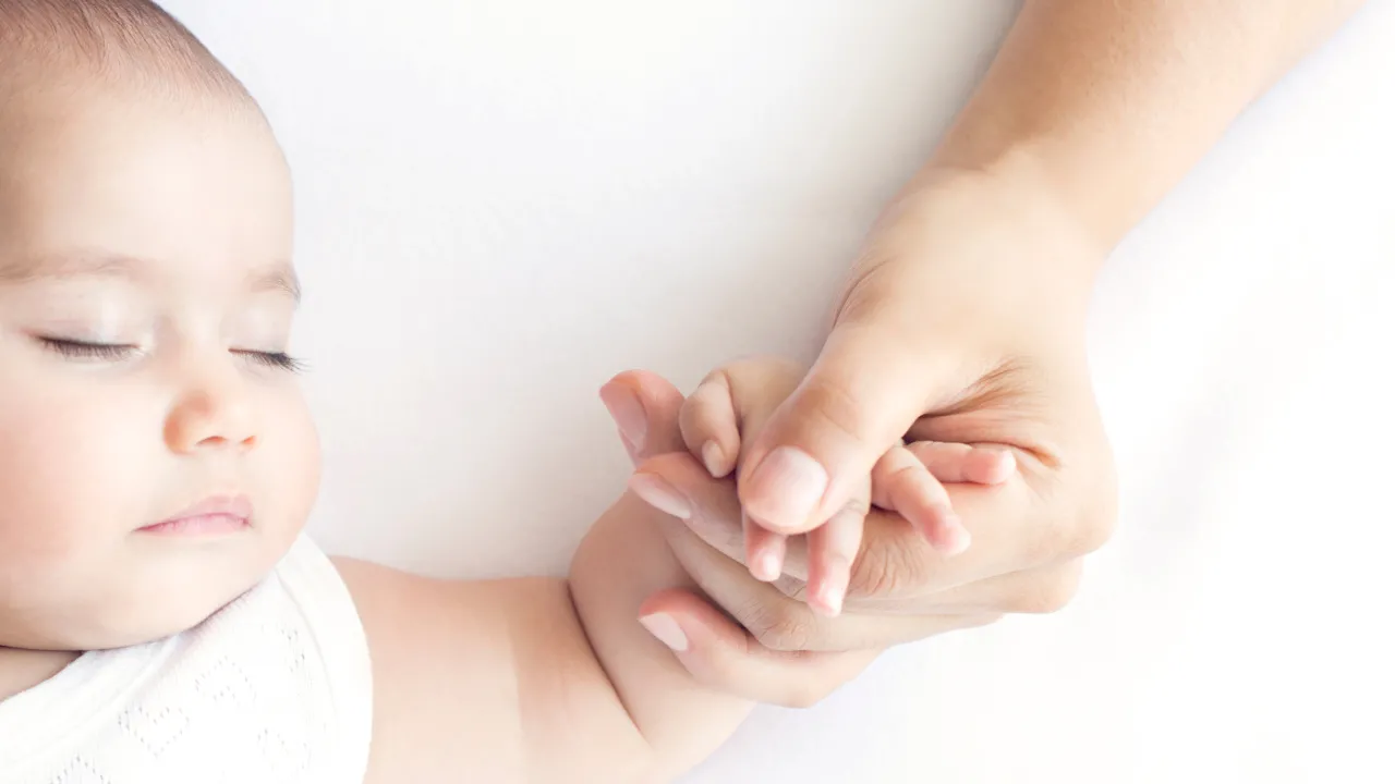 Imagem de um bebé de mão dada com a mãe