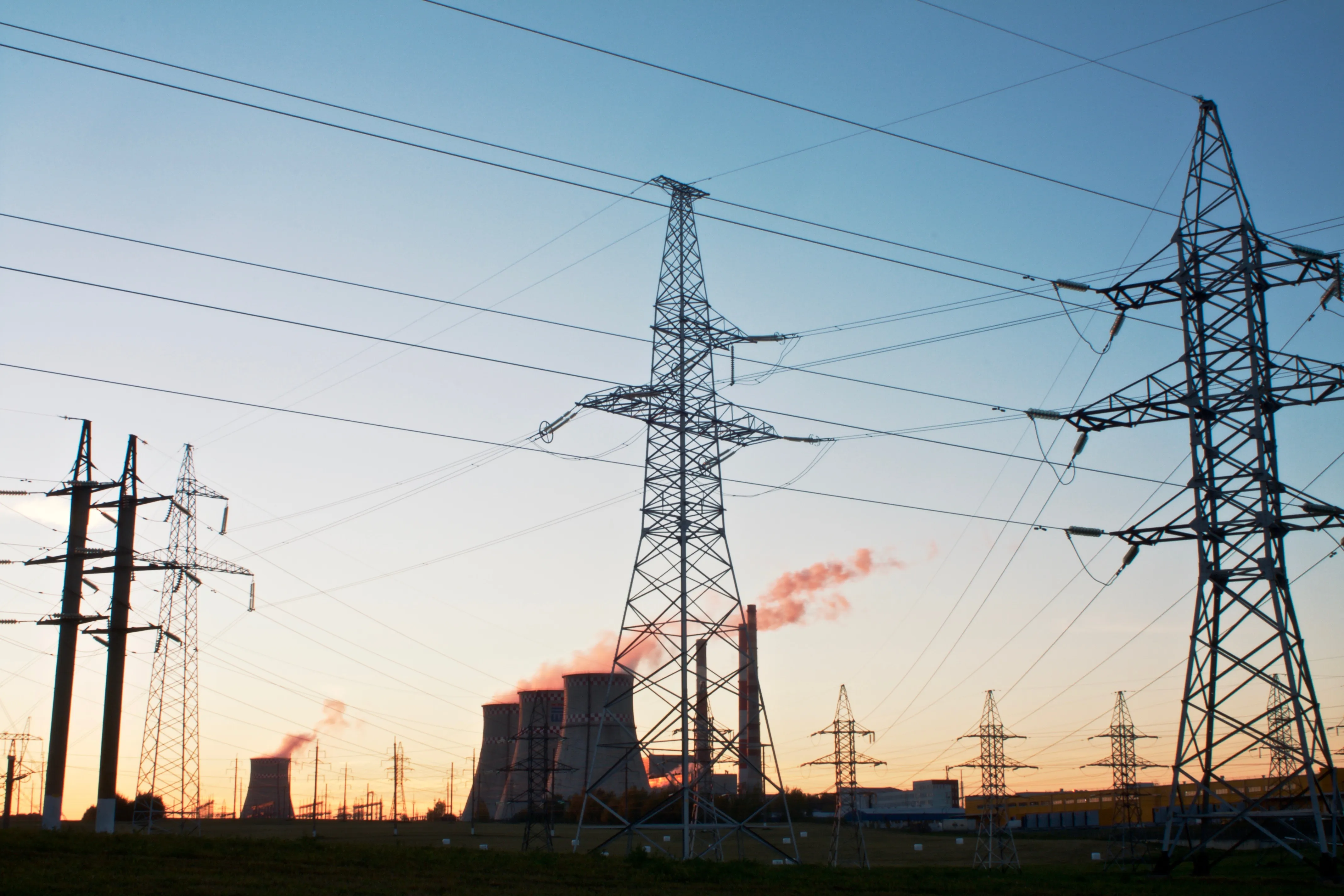 Uma paisagem com torres de refrigeração e uma central elétrica, tendo como fundo um céu azul. Crédito: Shutterstock