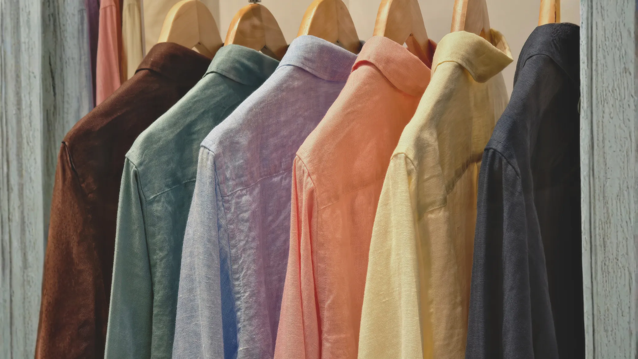 Imagem de várias camisas coloridas penduradas num cabide. Crédito: Shutterstock, com expansão de iamgem com recurso a IA.