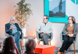 Uma plateia sentada a ouvir um debate entre quatro pessoas que estão em palco.