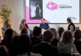 Quatro pessoas sentadas em palco a debater. Ao fundo, uma tela com a capa do livro da Fundação «Aquilo que Vi no Escuro, Histórias sobre a psicose».