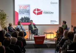 Quatro pessoas sentadas num palco. Atrás, um ecrã com a capa de um livro da Fundação e com o texto "Praça da Fundação".