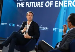 O jornalista britânico Ed Conway em palco, sentado, com um microfone na mão. O entrevistador de costas. Fundo azul com o texto "The Future of Energy". DR/FFMS