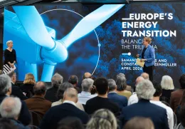Uma plateia de costas a assistir à apresentação de duas mulheres, num palco. Texto "Europe's Energy Transition".