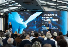 Uma plateia de costas a assistir à apresentação de duas mulheres, num palco. Texto "Europe's Energy Transition".