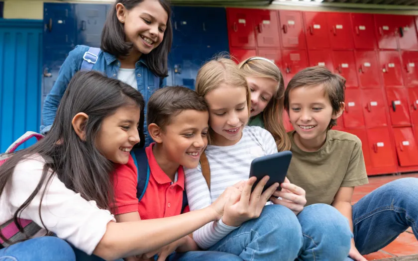 Um grupo de crianças na escola a utilizar smartphones e as redes sociais