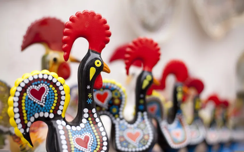 Imagem de várias figuras em barro do galo de Barcelos, numa loja de artigos para turistas.