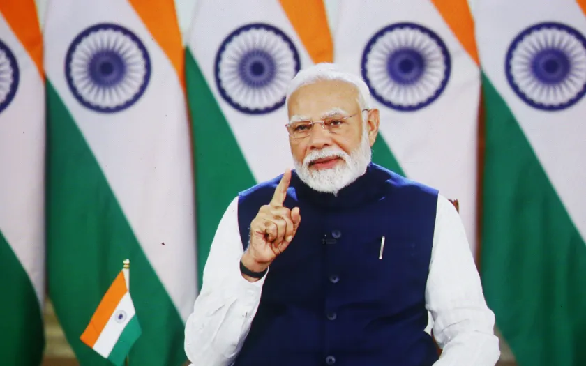 O primeiro-ministro da Índia Narendra Modi tendo como fundo um conjunto de bandeiras do país. Crédito: Shutterstock