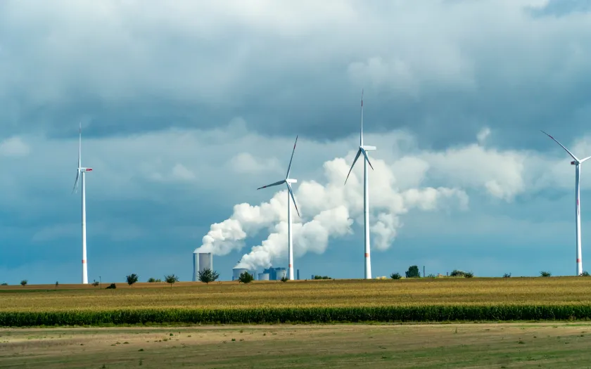  Turbinas eólicas e tubos industriais com fumo a sair num dia nublado na Alemanha. Créditos shutterstock