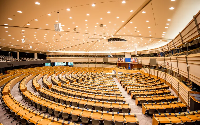 Imagem do interior do Parlamento Europeu. Ao fundo, as bandeiras de cada um dos Estados-membros.