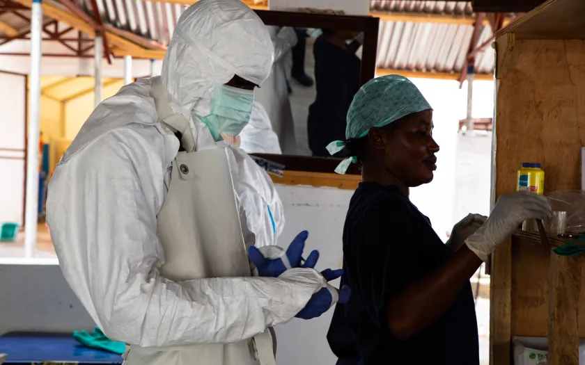 Imagem de uma enfermeira e de um médico vestidos com equipamentos de segurança durante um surto de Ébola em África. Belen B. Massieu/shutterstock