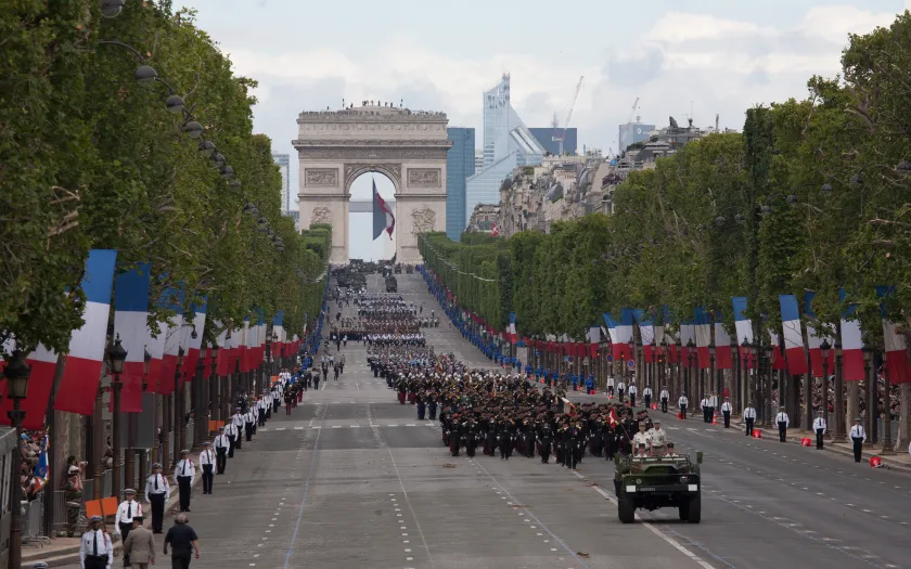 Desfile na avenida Champs-Elysees, em Paris, no dia da Bastilha. Soldados a desfilar e várias bandeiras do país.