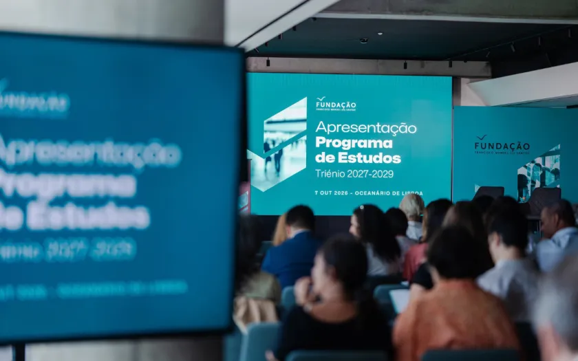 Dezenas de pessoas estão sentadas frente a um ecrã onde se lê  a frase: apresentação do Programa de Estudos da Fundação.