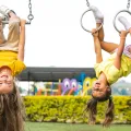 Imagem de duas crianças penduradas de cabela para baixo num balouço de argolas.