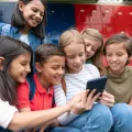 Um grupo de crianças na escola a utilizar smartphones e as redes sociais