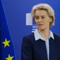 A presidente da Comissão Europeia Ursula von der Leyen a falar, num pulpito, com a bandeira da UE ao fundo.