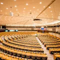 Imagem do interior do Parlamento Europeu. Ao fundo, as bandeiras de cada um dos Estados-membros.