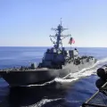 Imagem de um barco da marinha americana, com uma bandeira dos EUA hasteada.