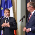 Emmanuel Macron e Friedrich Merz, lado a lado, durante uma conferência de imprensa conjunta. Bandeira de França, Alemanha e da UE ao Fundo. Créditos: shutterstock
