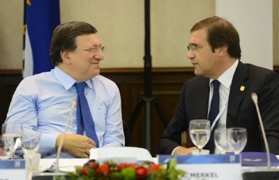 Dois homens sentados a conversar. Ambos de fato, com copos de água e microfones à frente. ©European People's Party
