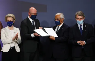 Uma mulher e três homens com máscaras na cara. Dois deles seguram um documento. Créditos: Comissão Europeia