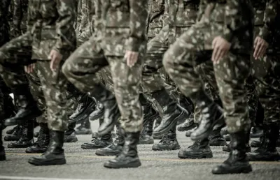 Um grupo de soldados a marchar numa rua. Crédito: Canva