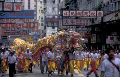 Pessoas desfilam empunhando um dragão de tecido e papel pelas ruas de  Hong Kong, em 1997.   Crédito: Shutterstock
