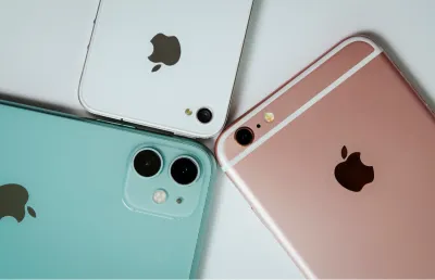 Imagem de três telemóveis iphone de várias cores, sob um fundo branco: Crédito: Shutterstock.
