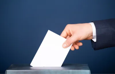 Imagem de uma urna de voto, sob fundo azul. Crédito: Canva
